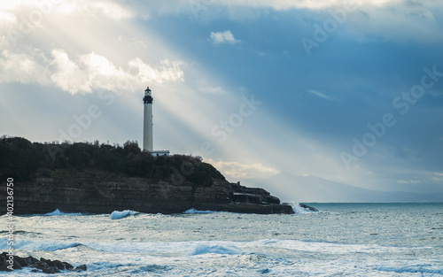 Biarritz lighthouse with sun rays in France, Atlantic Ocean in the foreground
