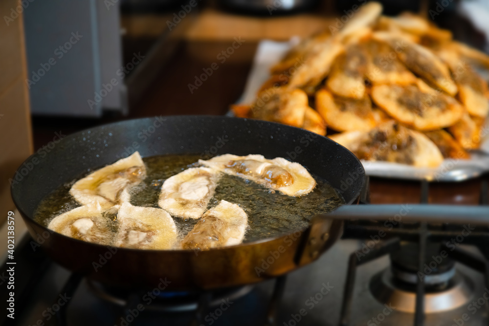 Gyoza dumplings with mushroom filling frying in hot pan. Golden crunchy dumplings cooking in oil.