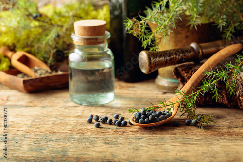 Juniper tincture and juniper berries on an old wooden table. photo