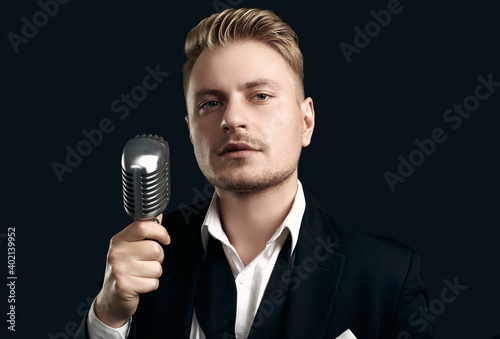 Handsome singer in elegant tuxedo and bow tie with vintage microphone