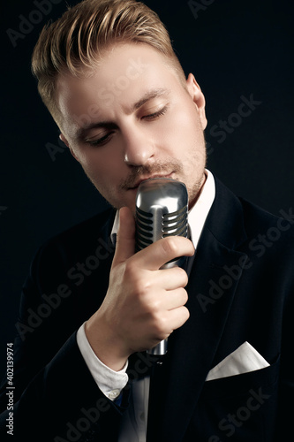 Handsome singer in elegant tuxedo and bow tie with vintage microphone