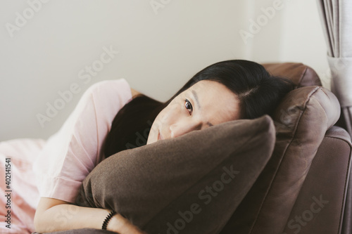 Woman lying on sofa in living room with eye open.
