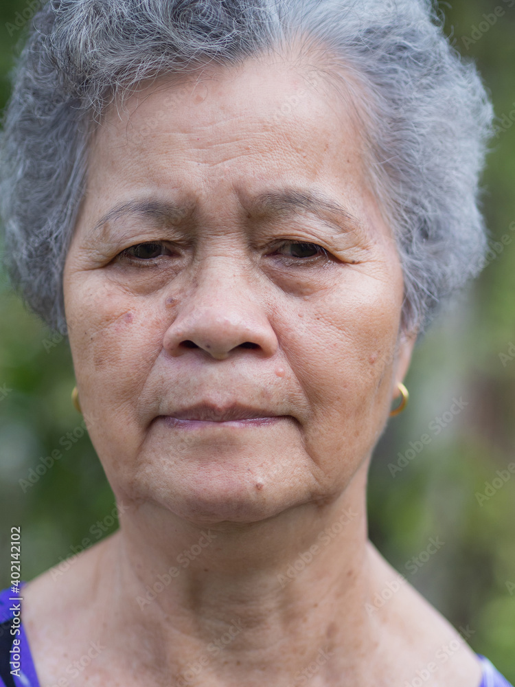 Senior woman with short white hair, anxious face, and looking away while standing in a garden. Concept of old people and healthcare Senior woman with short white hair, anxious face, and looking away while standing in a garden. Concept of old people and healthcare