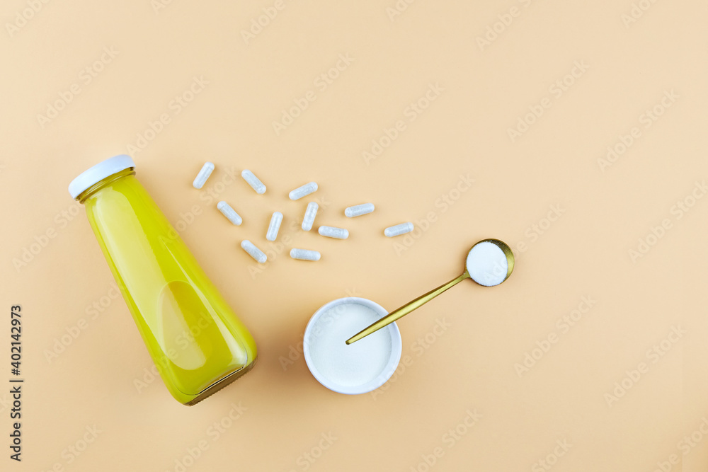 Collagen protein powder and capsules, a bottle of orange juice. Dietary supplement for skin and joints.