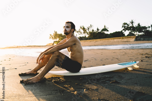 Photography Shirtless male with surfing board relaxing on quiet beach