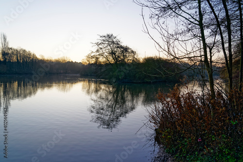 Low winter sun begins to rise over a misty lake © Steven Bramall