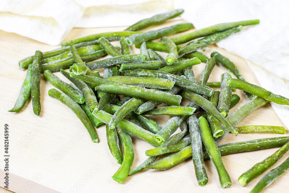 Frozen green beans pods on light wooden background. Frozen green beans pods on light wooden background.