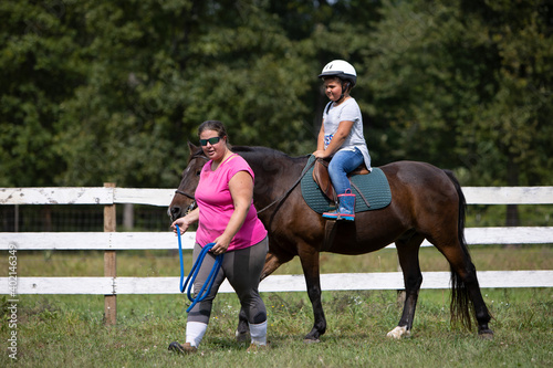 child riding a horse with instructor