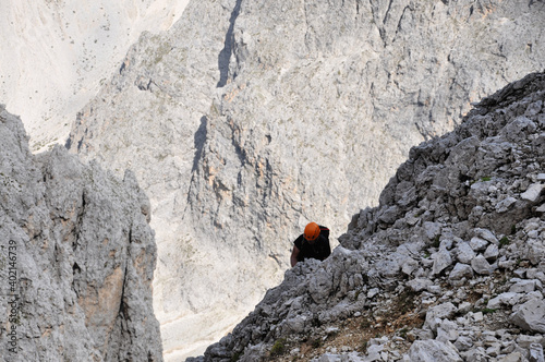 Mężczyna w pomarańczowym kasku na ferracie w Dolomitach, Włochy