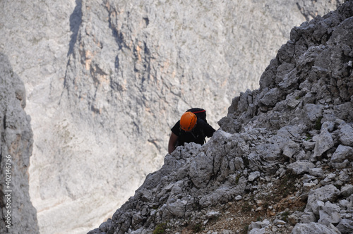 Człowiek w pomarańczowym kasku na ferracie w Dolomitach, Włochy