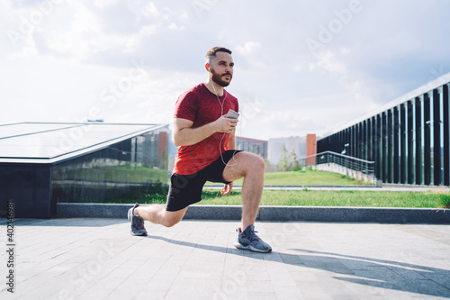 Confident male athlete stretching with phone and earphones