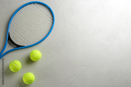 Tennis racket and balls on grey table, flat lay. Space for text © New Africa