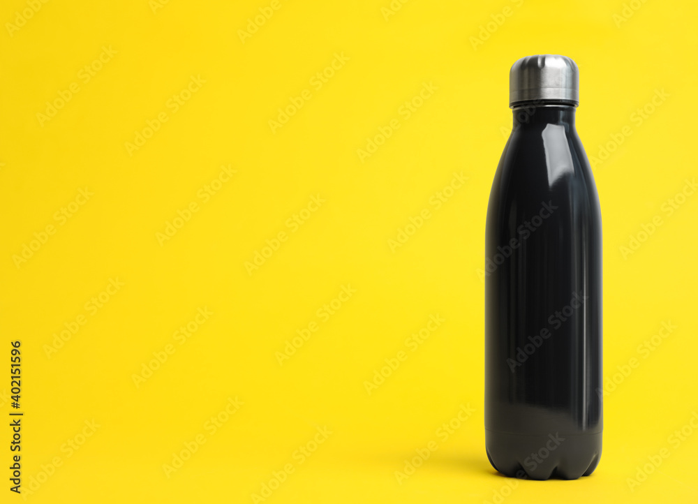 Stylish thermo bottle on yellow background, space for text Stylish thermo bottle on yellow background, space for text