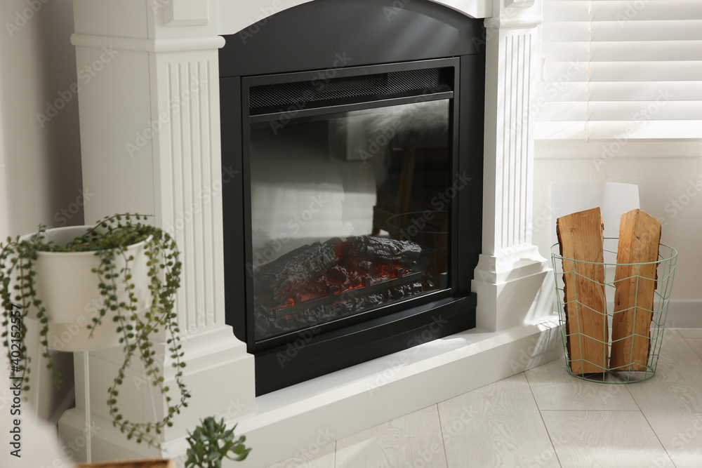 Bright living room interior with artificial fireplace and firewood in basket Bright living room interior with artificial fireplace and firewood in basket