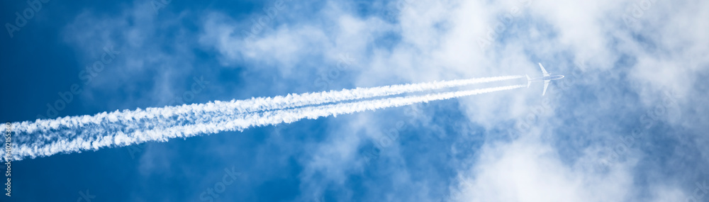 Stunning view of a jet forming contrails in a blue sky. Cloudy sky with copy space.