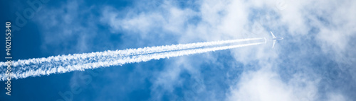 Obraz na płótnie Stunning view of a jet forming contrails in a blue sky. Cloudy sky with copy space. w salonie
