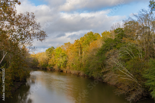A bend in the Neuse River in Raleigh, North Carolina in autumn with the sun shining on the orange leaves of the trees