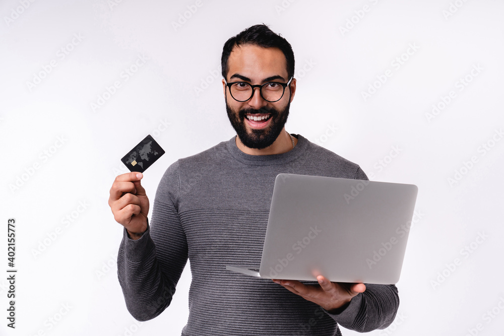 Happy islamic man holding a laptop with credit card isolated over white background Happy islamic man holding a laptop with credit card isolated over white background