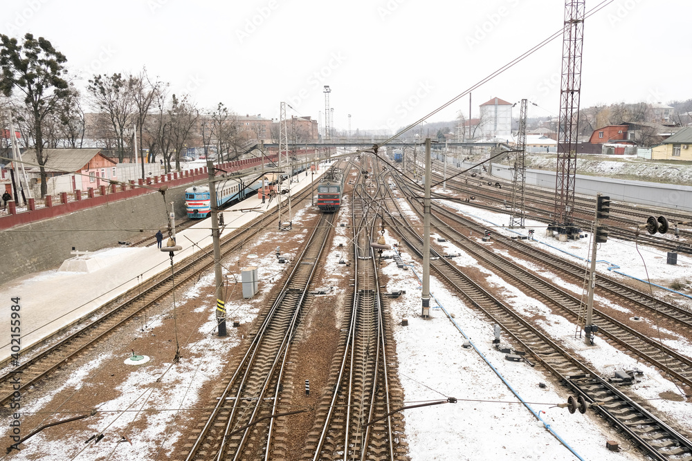 Obraz premium Railway station and crossing railway track. Platform and electric train. Transportation background