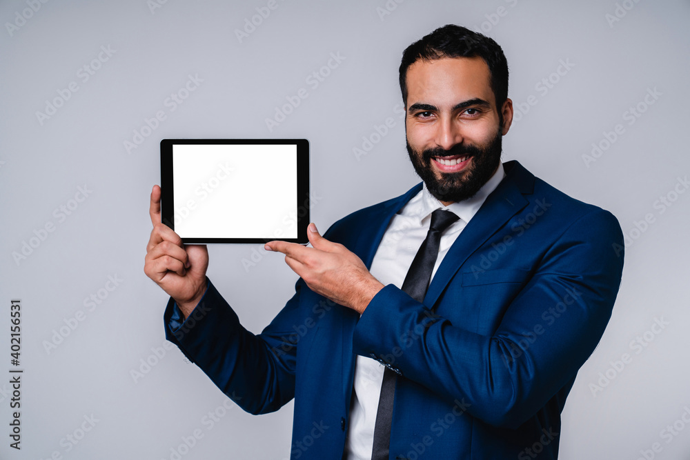 Intelligent smart 25s Arabian businessman in formal clothes holding blank tablet isolated over grey background Intelligent smart 25s Arabian businessman in formal clothes holding blank tablet isolated over grey background