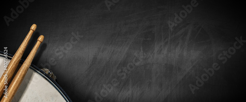 Canvas Print Closeup of two wooden drumsticks and an old metallic snare drum on an empty blackboard with copy space
