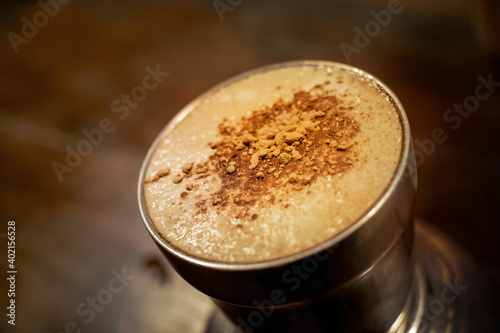 Stainless steel cup of cappuccino with foam and cinnamon