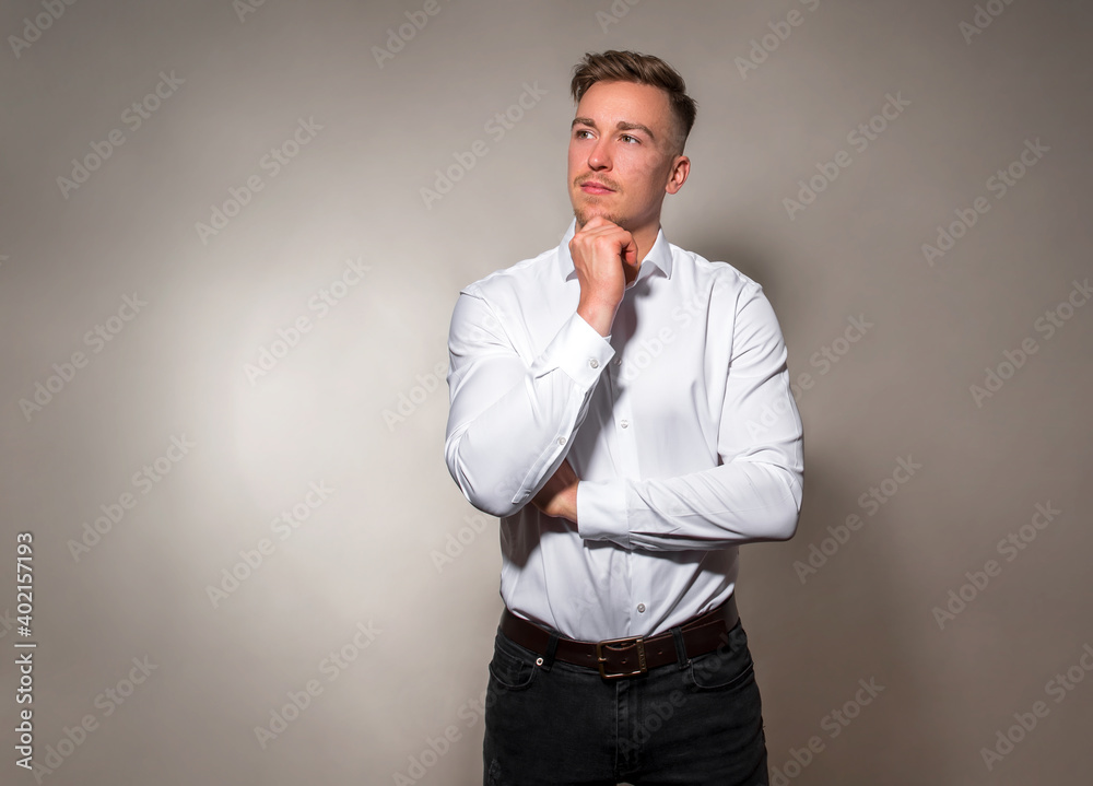 Handsome young man posing on grey background in white dress shirt 