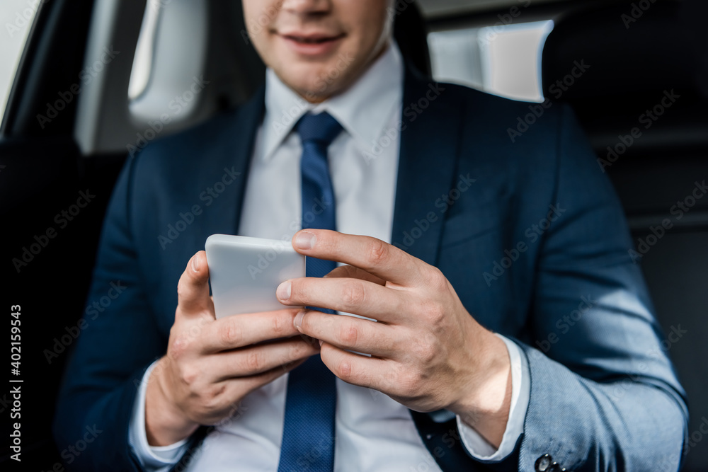 Cropped view of smartphone in hands of businessman on blurred background in auto. Cropped view of smartphone in hands of businessman on blurred background in auto.
