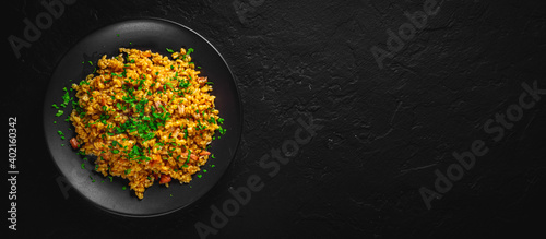 Panel kuchenny z motywem Bulgur with vegetables and meat on black plate on Dark grey black slate background