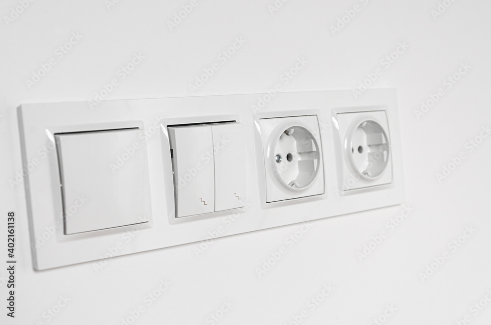 White plastic walk-through switches and sockets on a white wall White plastic walk-through switches and sockets on a white wall