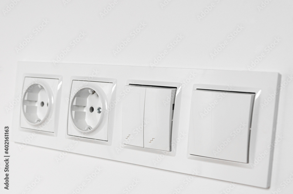 White plastic walk-through switches and sockets on a white wall White plastic walk-through switches and sockets on a white wall