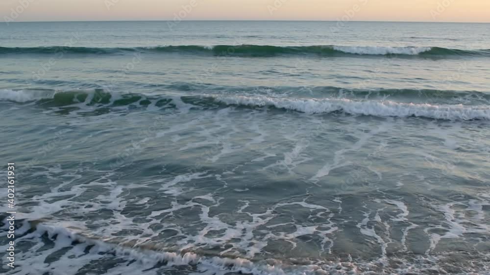 Gentle sea waves lap near the shore of the sea at sunset Gentle sea waves lap near the shore of the sea at sunset