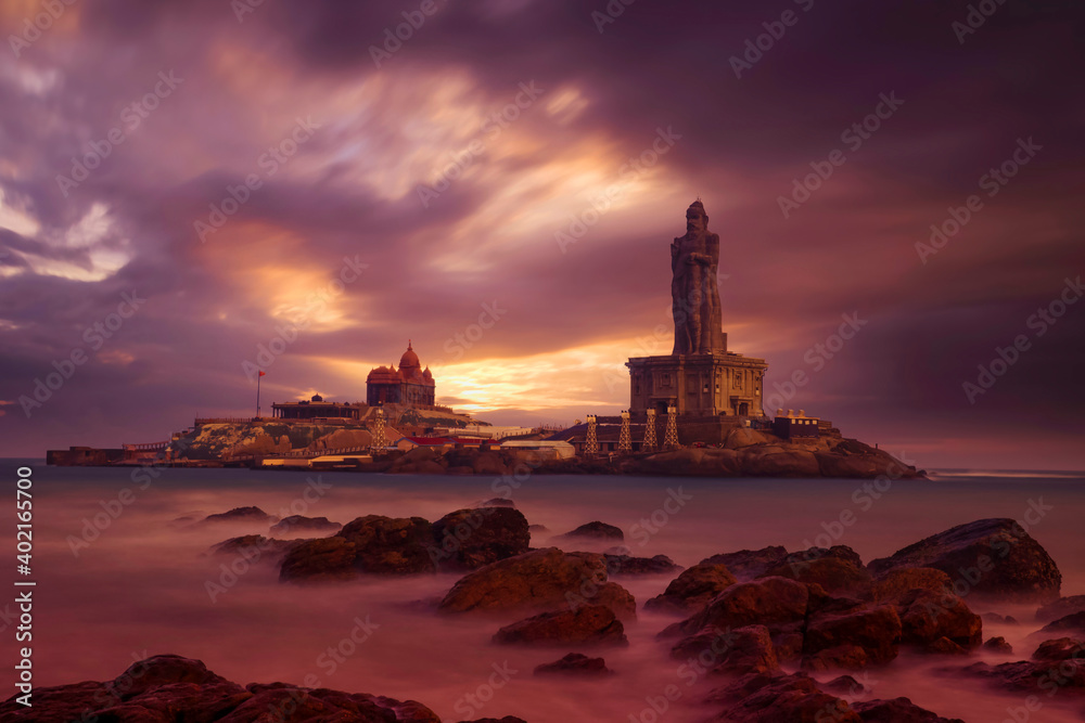Kanyakumari - Vivekananda Rock Memorial Thiruvalluvar Statue in the evening with a colorful and cloudy sky background.