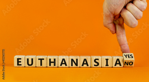 Euthanasia yes or no symbol. Male hand turns cubes and changes words 'Euthanasia yes' to 'Euthanasia no'. Medical and euthanasia yes or no concept. Beautiful orange background, copy space. photo