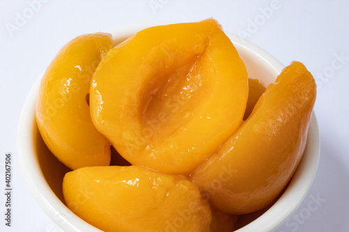 Halved peaches in syrup in white bowl