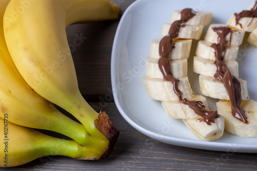 Yellow bananas and sliced bananas in chocolate glaze on a plate. side view