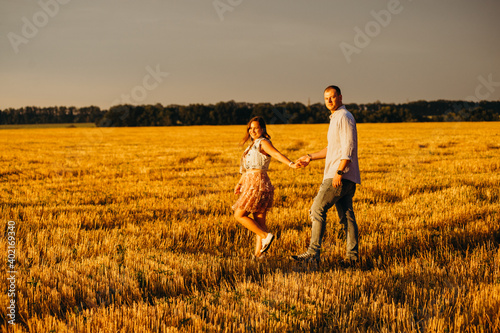 A happy couple in a field in the rays of the setting sun