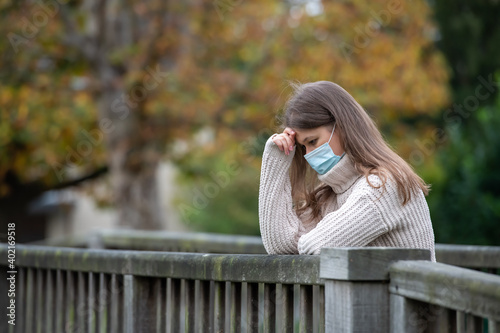 sad young woman wears mask on the bridge