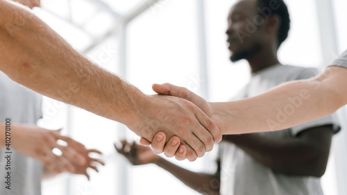 close up. two comrades shaking hands, standing in a circle of friends