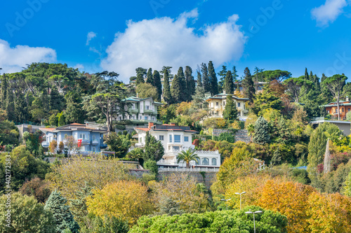 Modern buildings in the forest along the Bosphorus strait in Istanbul Turkey from ferry on a sunny day with background cloudy sky