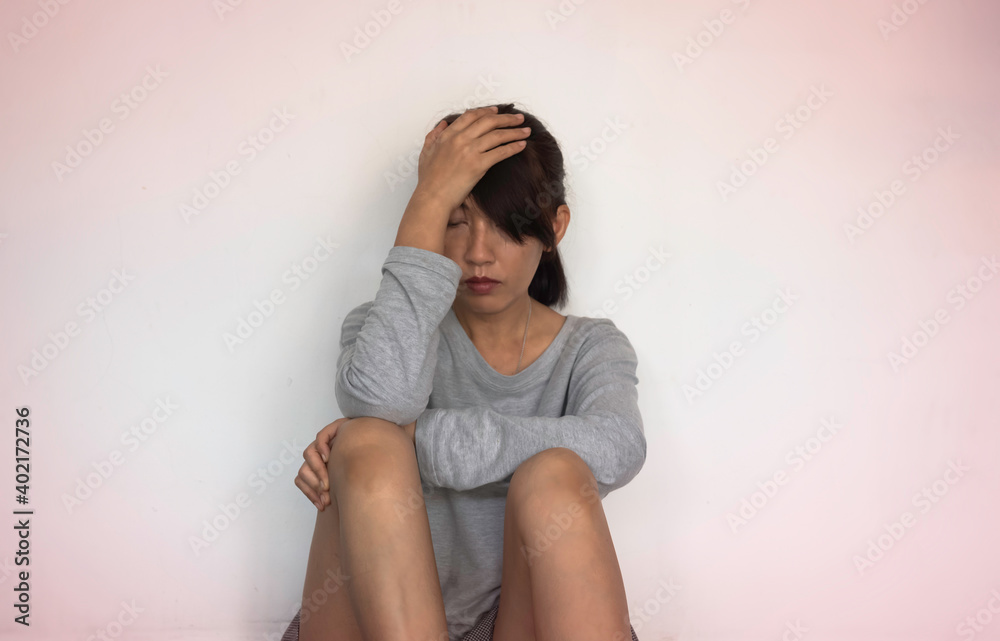 Unhappy woman sits and hugs her knees up to the chest,raise hand touch head,with upset and sad feeling
