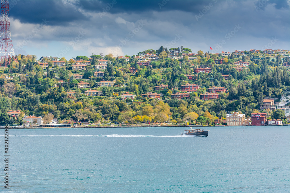 Modern buildings in the forest along the Bosphorus strait in Istanbul Turkey from ferry on a sunny day with background cloudy sky