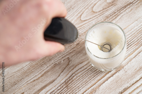 Milk frother making milk foam. Top view. Black mixer whipping milk. Milk frother device photo