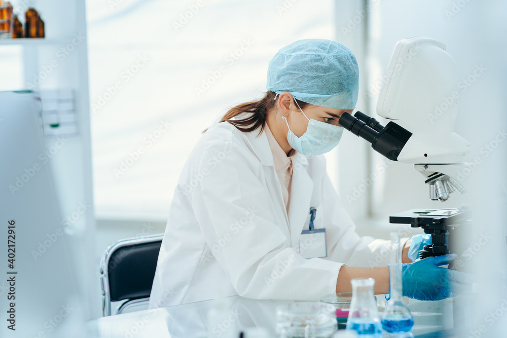 close up. female scientist looking through a microscope. close up. female scientist looking through a microscope.