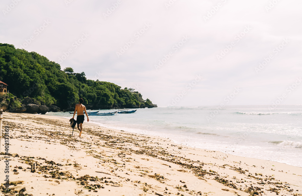 Unrecognizable man walking on sandy beach