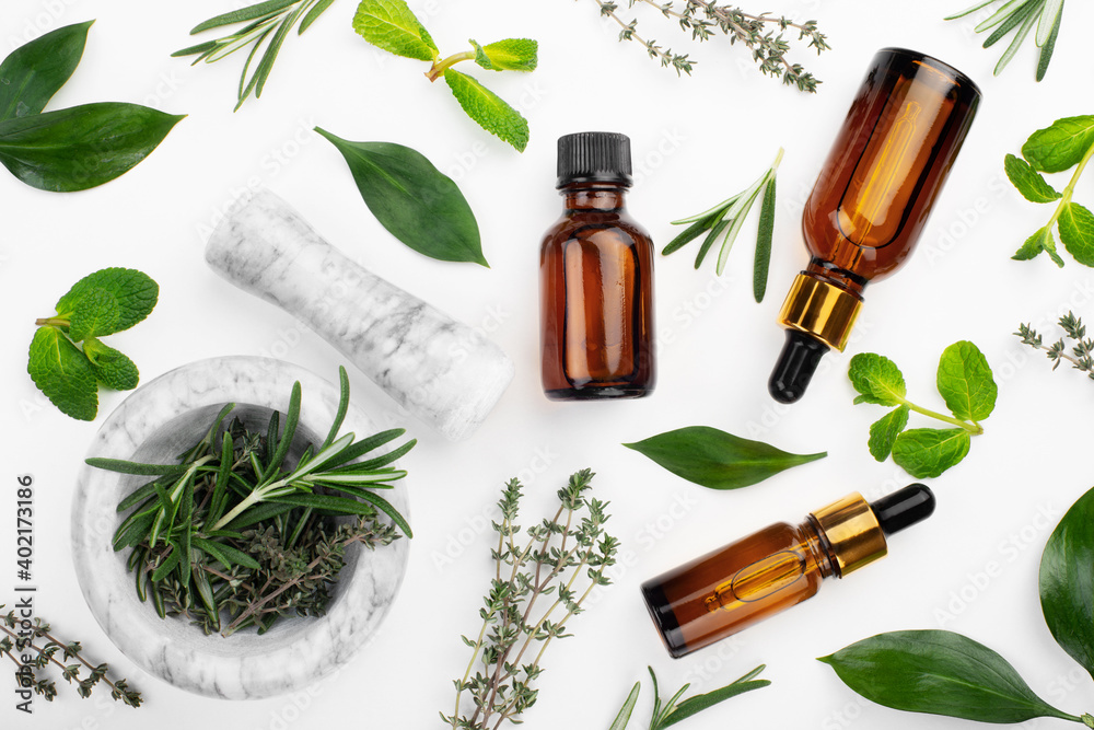 Dropper bottles with oil and mortar with herbs on white table flat lay view. Herbal cosmetics concept Dropper bottles with oil and mortar with herbs on white table flat lay view. Herbal cosmetics concept