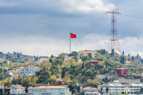 Turkish national flag and modern buildings along the Bosphorus strait in Istanbul Turkey from ferry on a sunny day with background cloudy sky