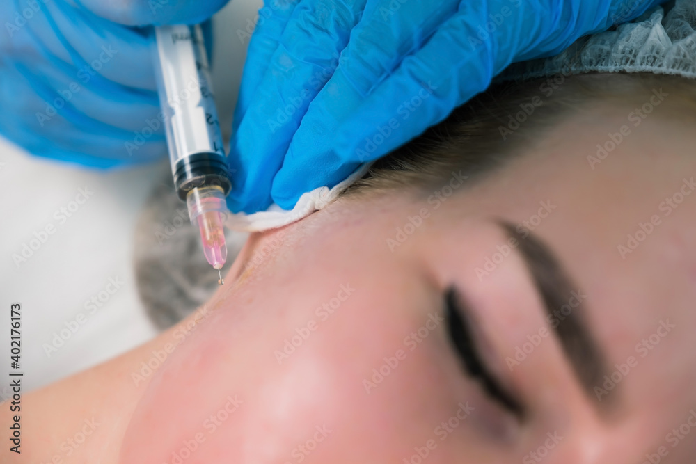 PRP therapy in beauty clinic. Cosmetologist is doing injections of blood plasma to womans face to cure problem skin, closeup view. Treatment of skin in cosmetology for young female. PRP therapy in beauty clinic. Cosmetologist is doing injections of blood plasma to womans face to cure problem skin, closeup view. Treatment of skin in cosmetology for young female.