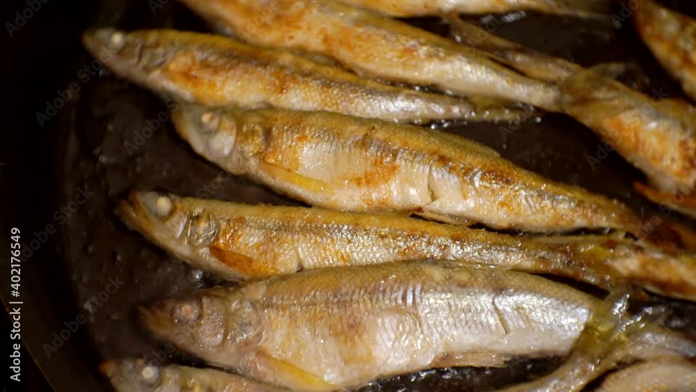 seafood cooking process.a few small fish are fried in oil in a pan.close-up. seafood cooking process.a few small fish are fried in oil in a pan.close-up.