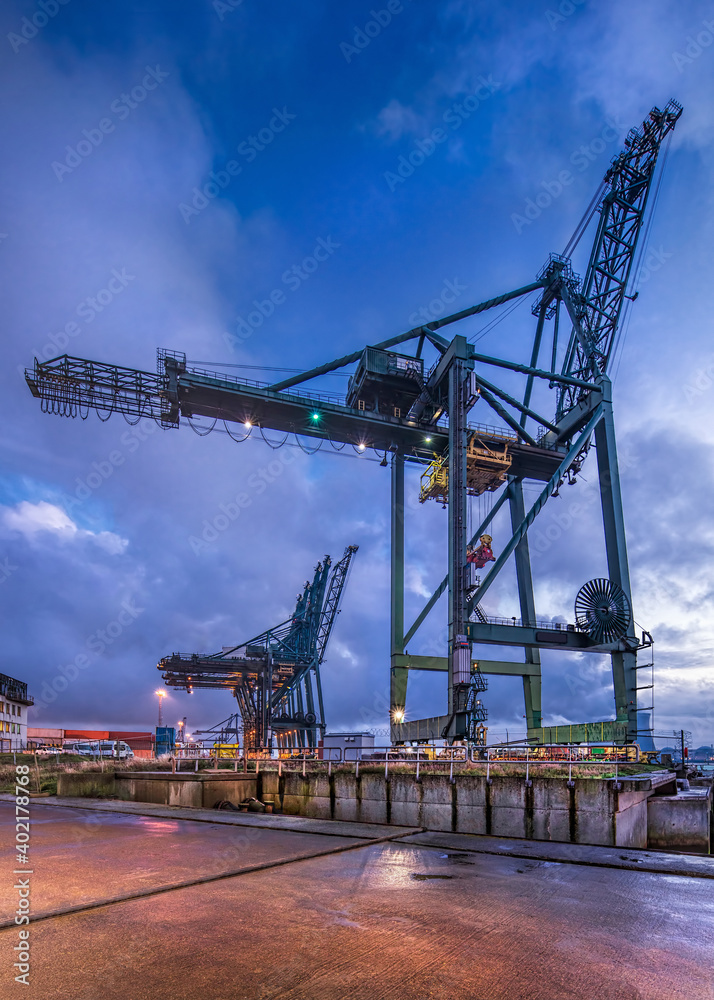 Twilight scene with container terminal and massive crane against a cloudy sky, Port of Antwerp, Belgium.